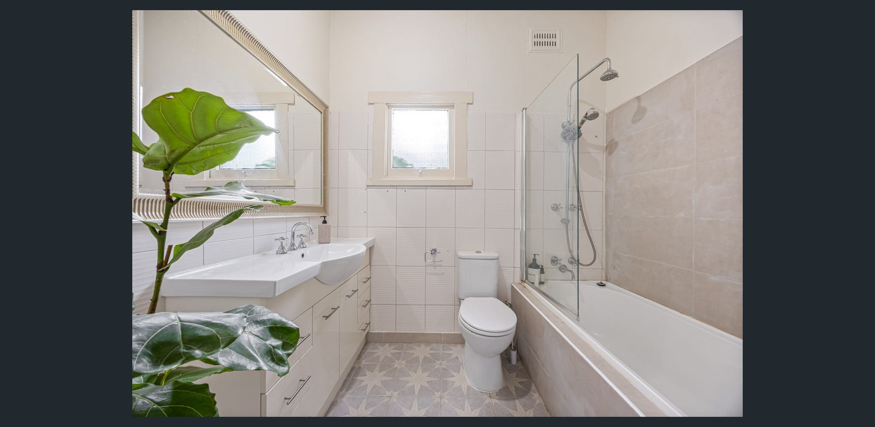 Original cottage bathroom with dated tiling and combined bath and shower
