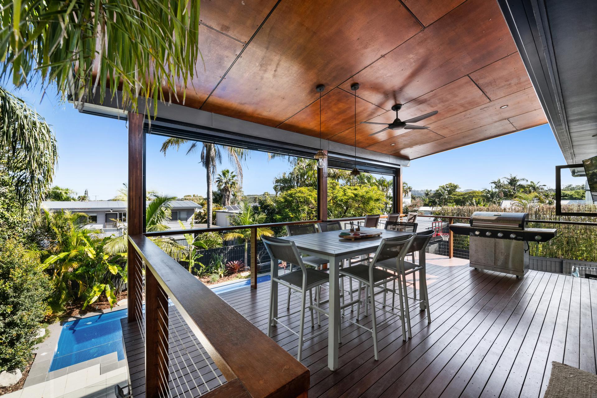 Upper covered deck with dining setting, timber ceiling and outlook over the pool