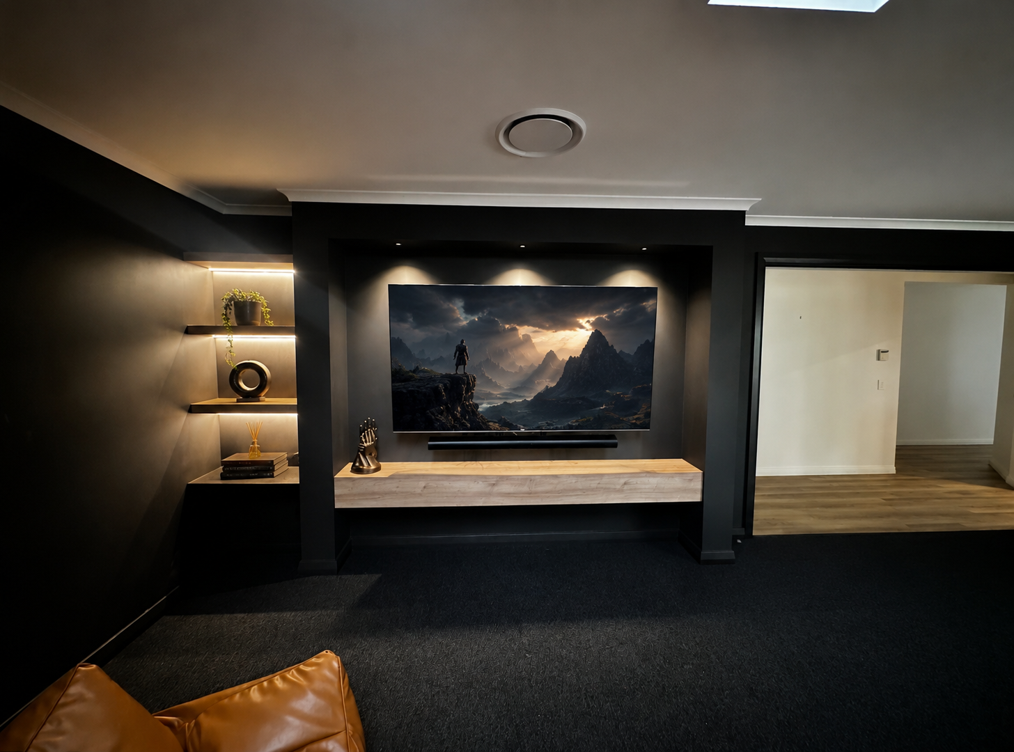 Finished media room with dark feature wall, timber bench, backlit shelving and large screen