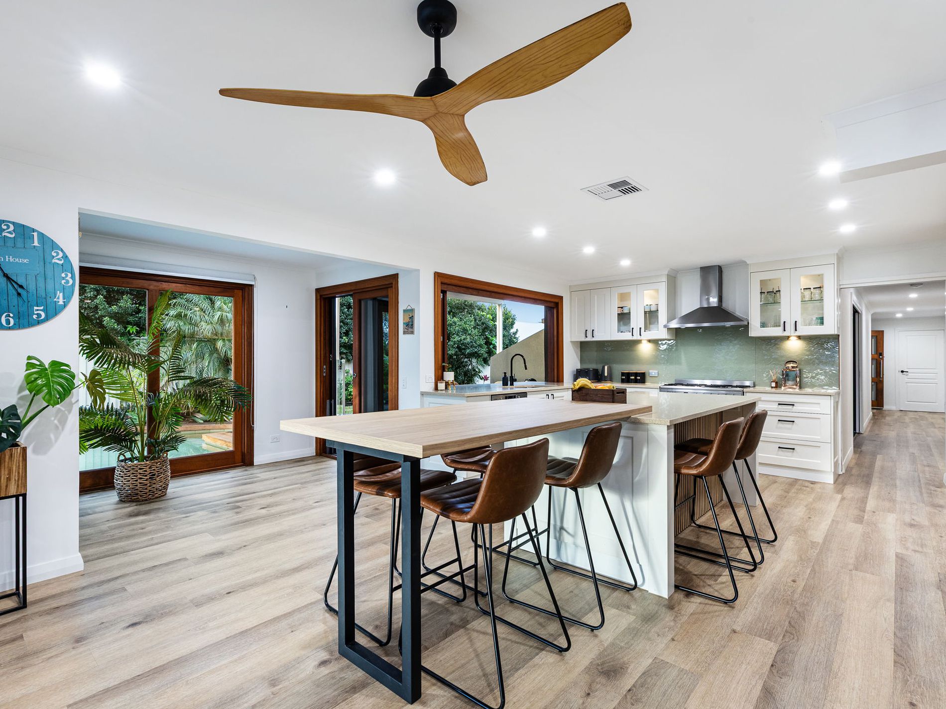 Open-plan kitchen and dining space with hybrid flooring, timber island bench and garden outlook