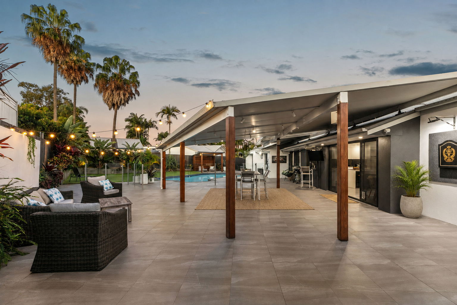 Covered alfresco area with timber posts, festoon lighting, lounge seating and pool beyond