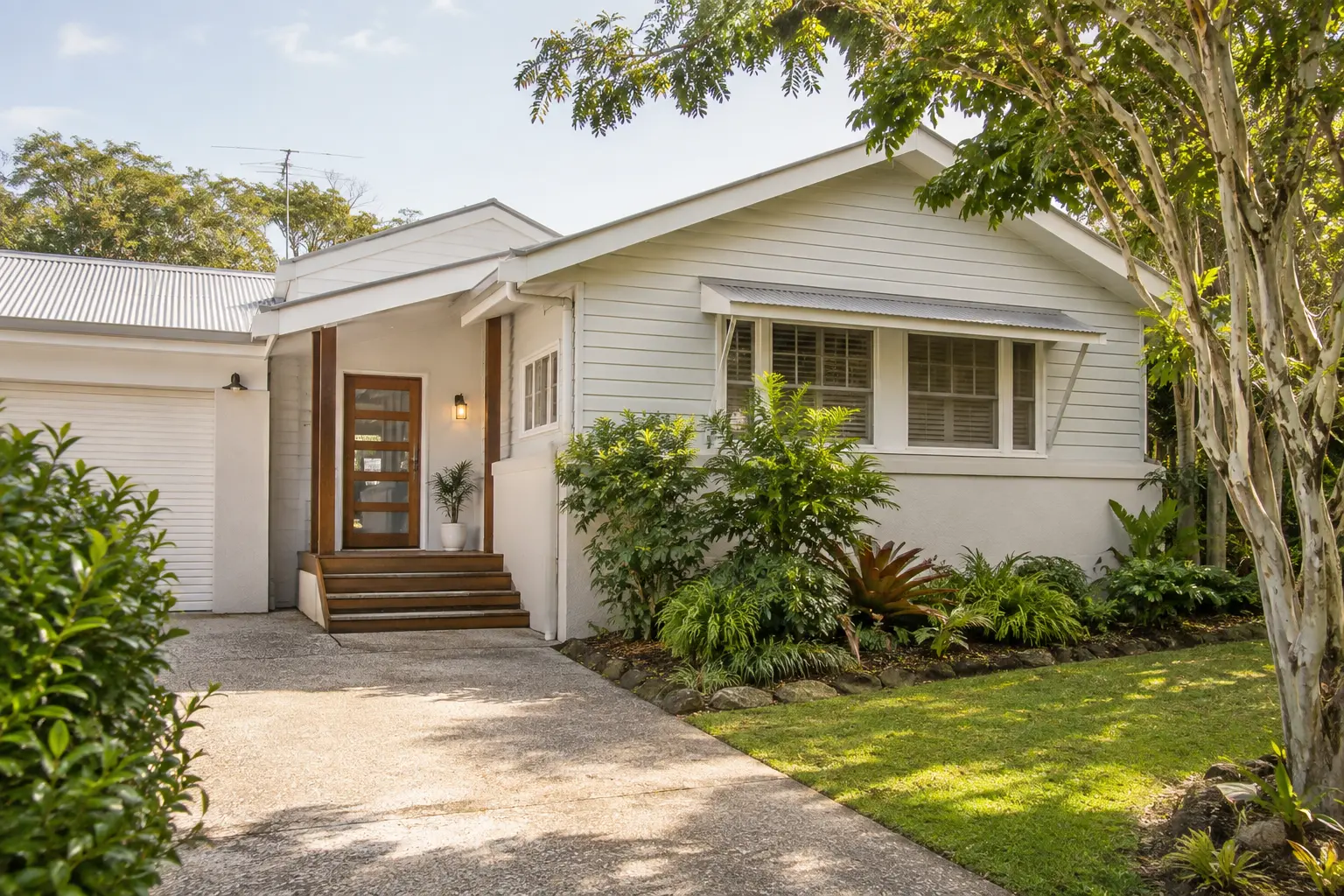 Street view of a well-maintained weatherboard home with tidy gardens